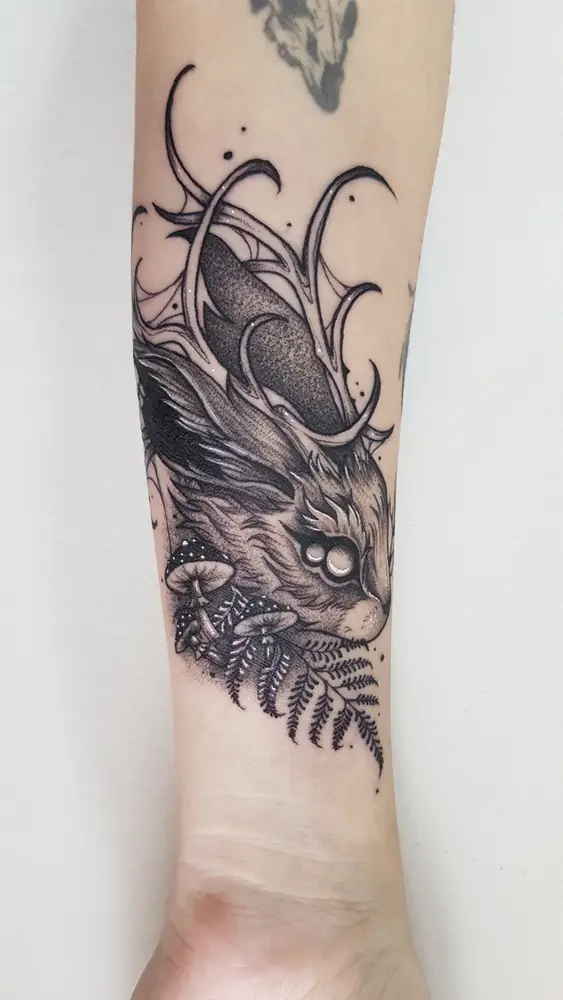 Tatuagem blackwork de criatura com samambaia no antebraço, por Bia, Clash Tattoo Ribeirão Preto