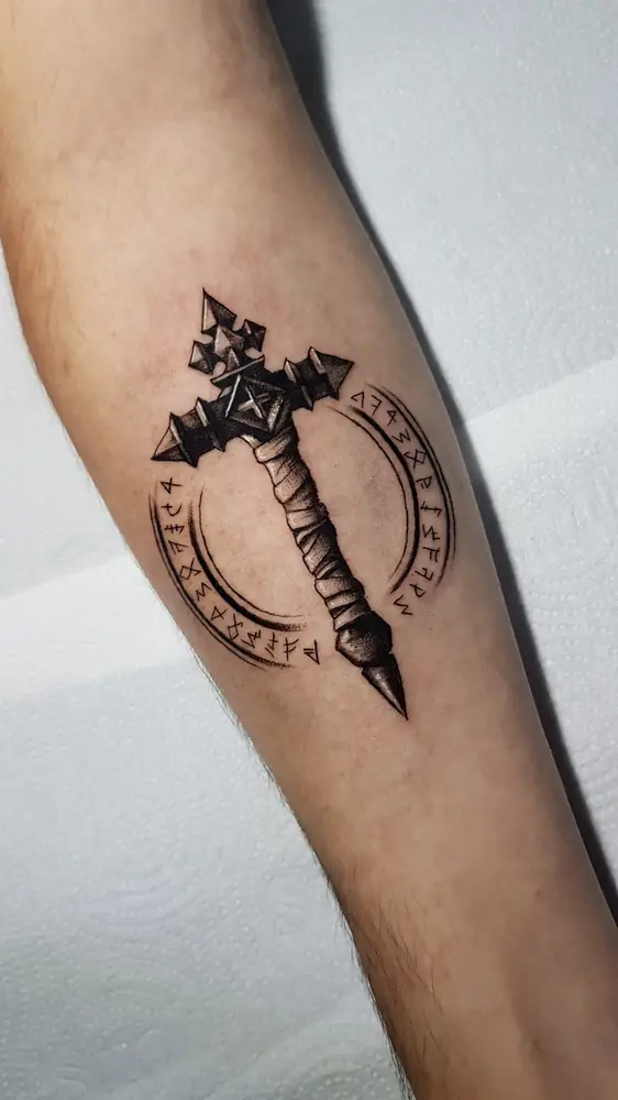 Tatuagem blackwork de espada com círculo rúnico no antebraço, por Bia, Clash Tattoo Ribeirão Preto